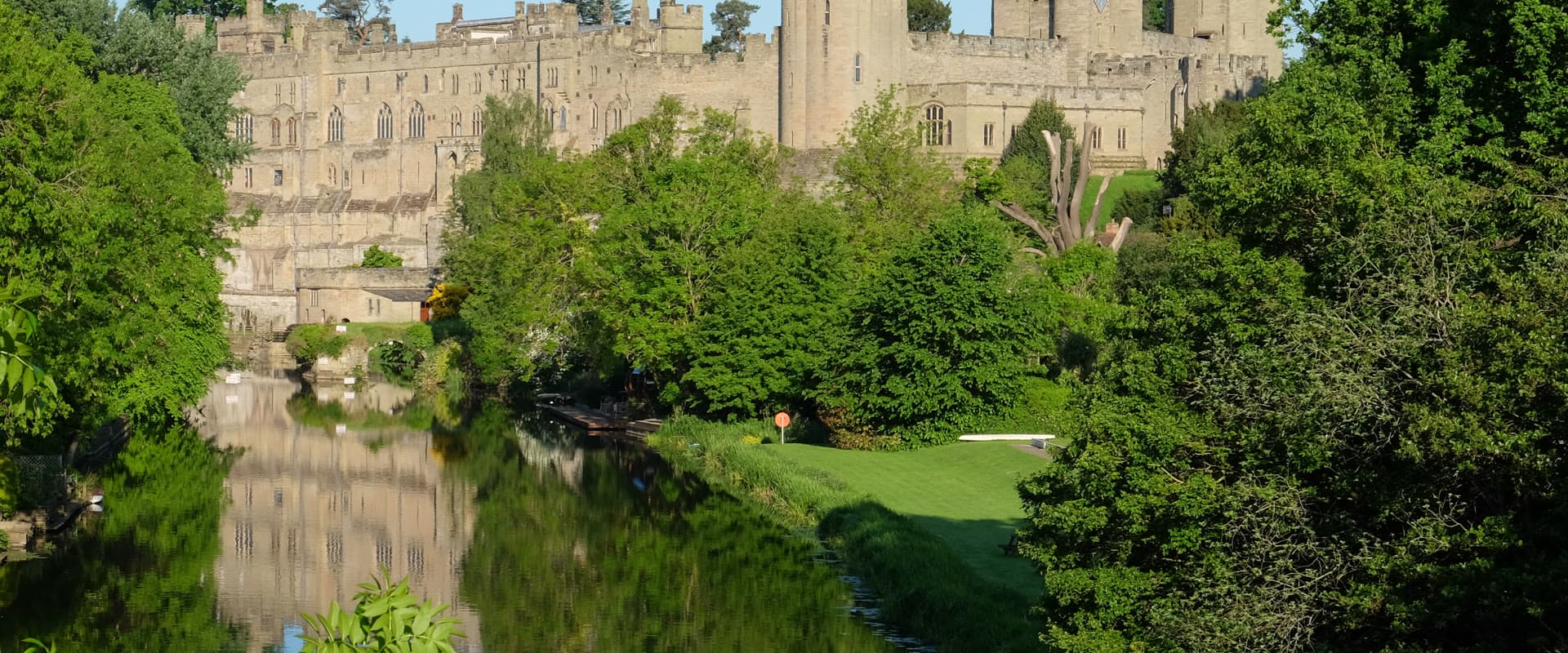 Warwick Castle's towers rising above the River Avon on a bright spring day