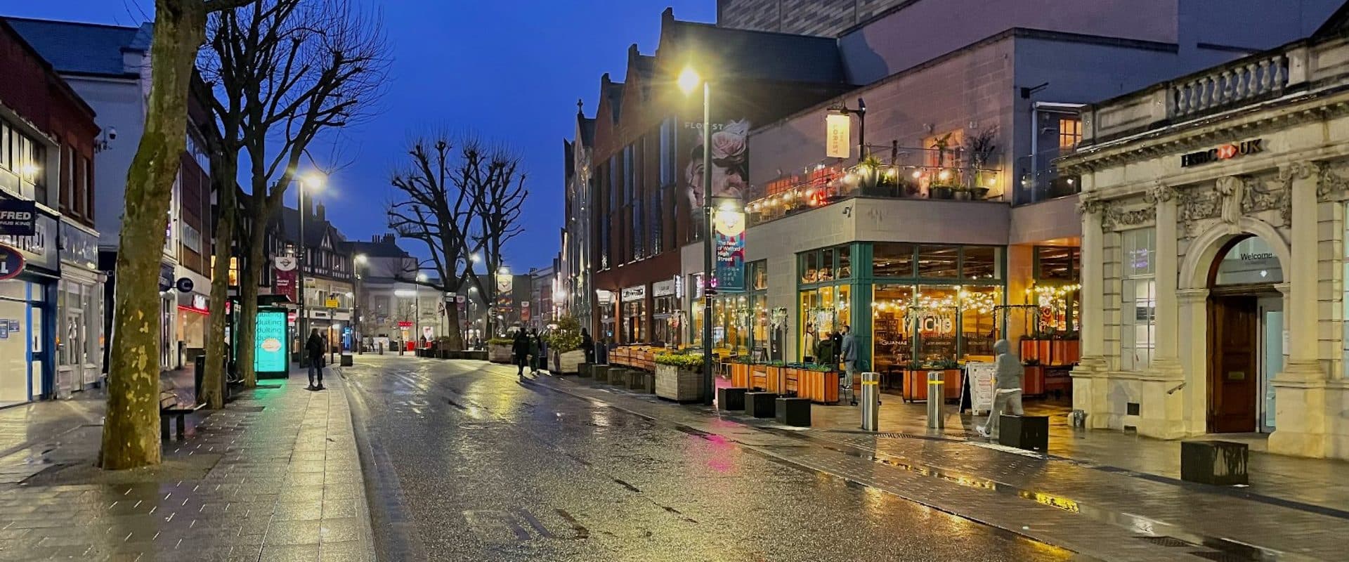 Evening view along Watford High Street with illuminated shopfronts