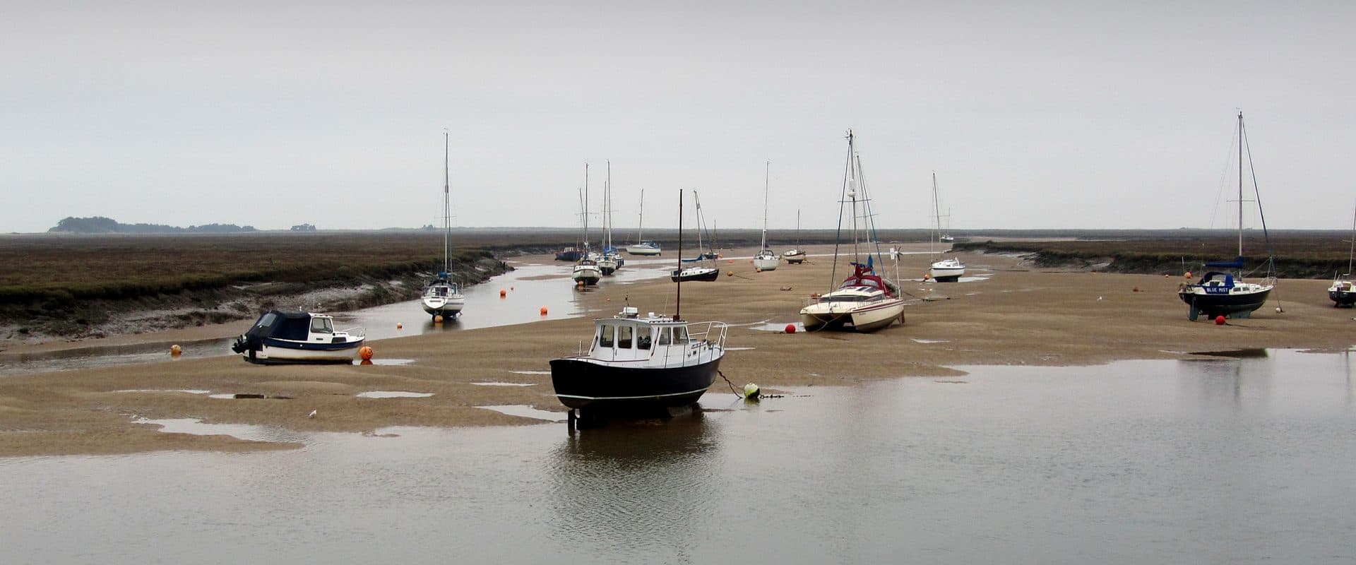 Boats moored across the harbour at Wells-next-the-Sea