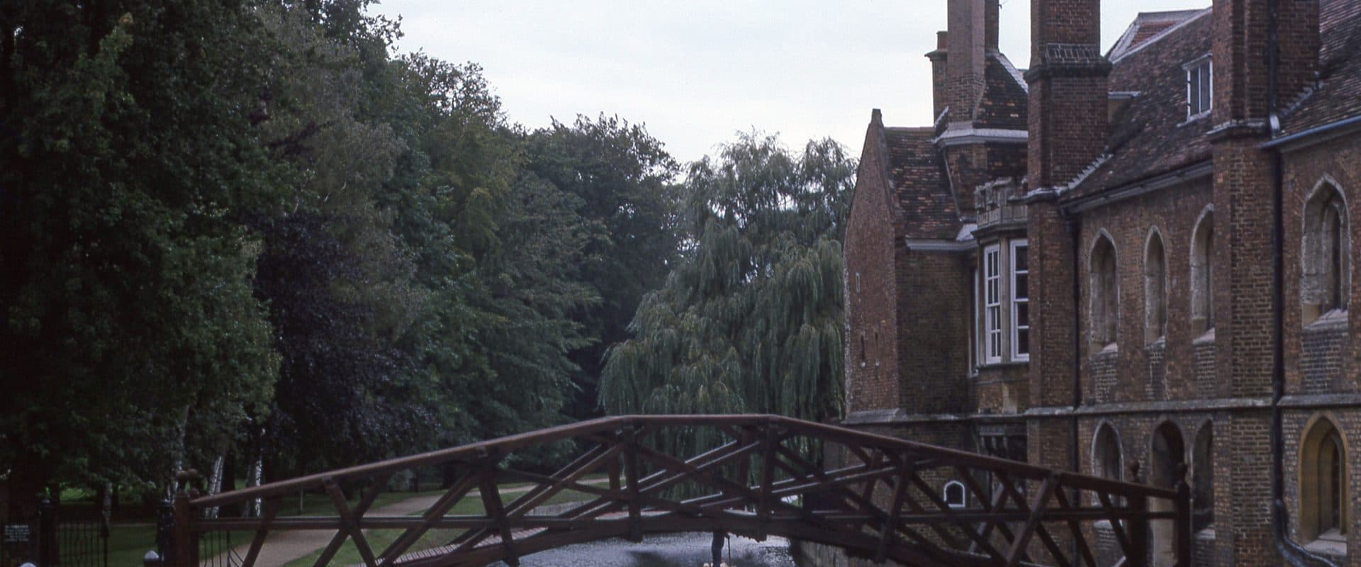 The timber lattice trusses of Cambridge's Mathematical Bridge arching over the River Cam between the twin towers of Queens' College