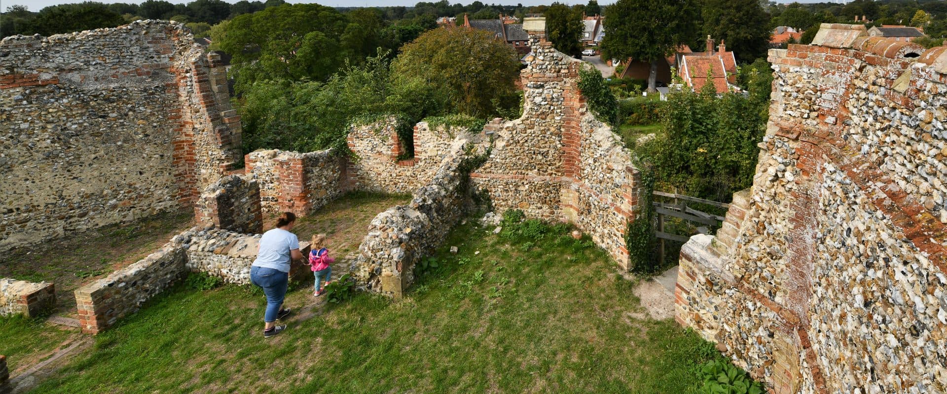 The grassy Norman motte and ruined curtain wall of Eye Castle in Suffolk