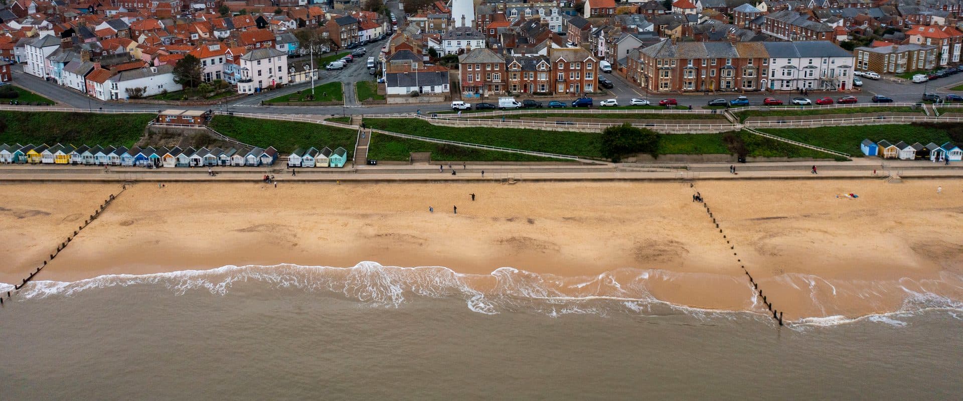Southwold's sandy beach and rooftops with the town's white lighthouse tower rising above the skyline