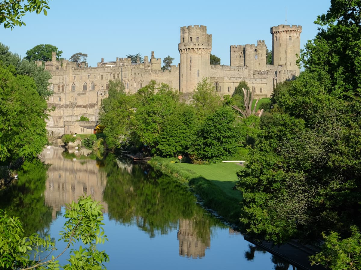 Warwick Castle's towers rising above the River Avon on a bright spring day
